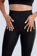 Person wearing black leggings and a black top on a white background